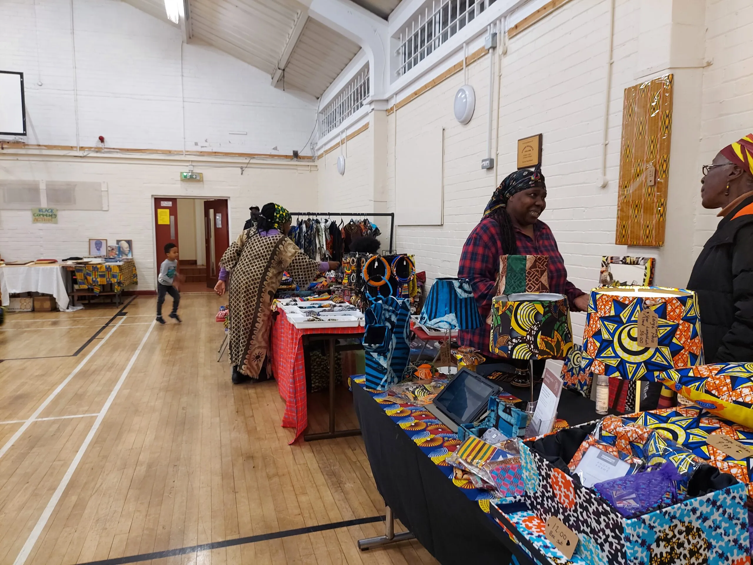 A community market filling the sports hall, with stalls of fabric, jewellery and crafts