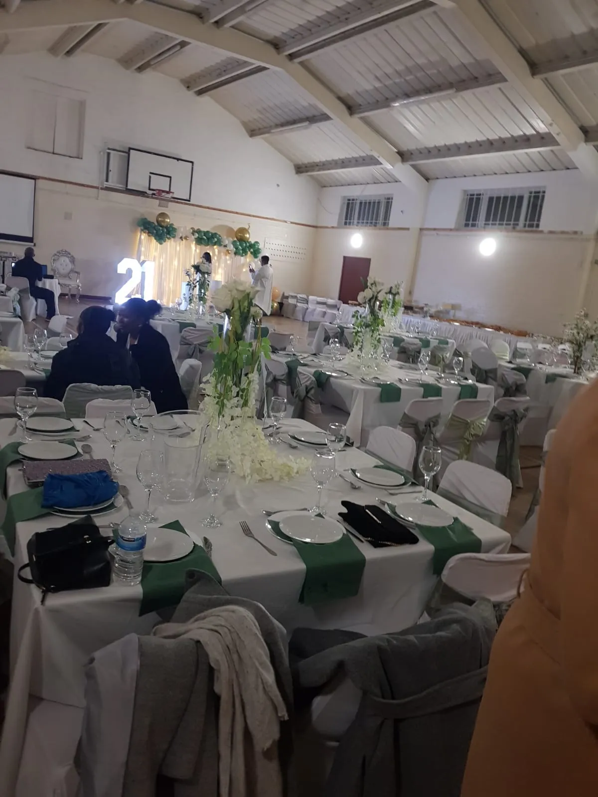 The sports hall laid out with round tables and floral centrepieces for a party