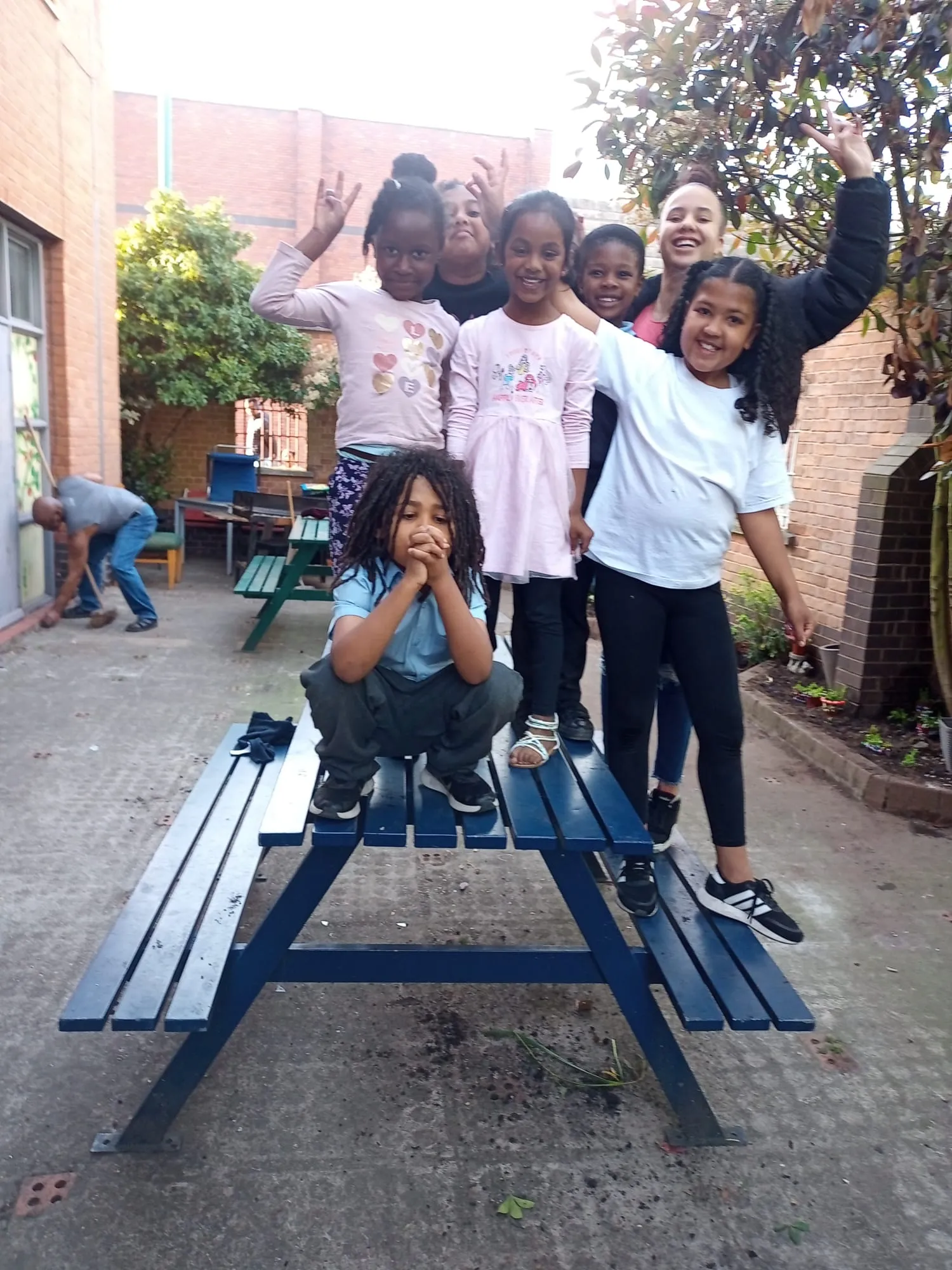 Children cheering on a picnic bench during a gardening session in the club’s yard